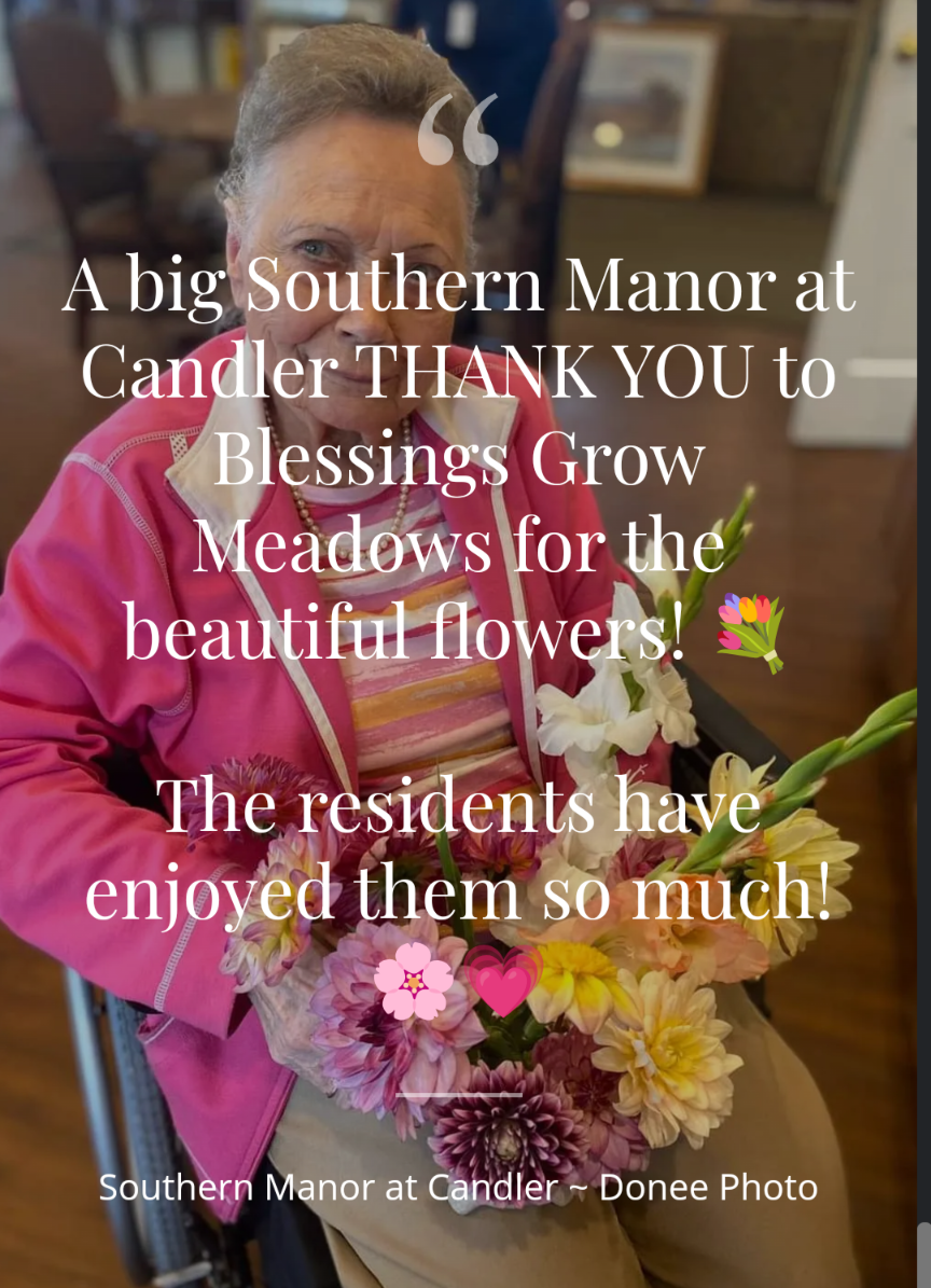 Photo of a resident at Southern Manor in Candler holding vibrant pink, yellow, and purple dahlias and gladioli in a wheelchair.
