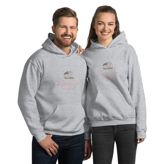 Apparel graphic design featuring a gray hoodie with a charming illustration of a house adorned with coral flowers and the text Blessings Grow Meadows in a soft coral script
