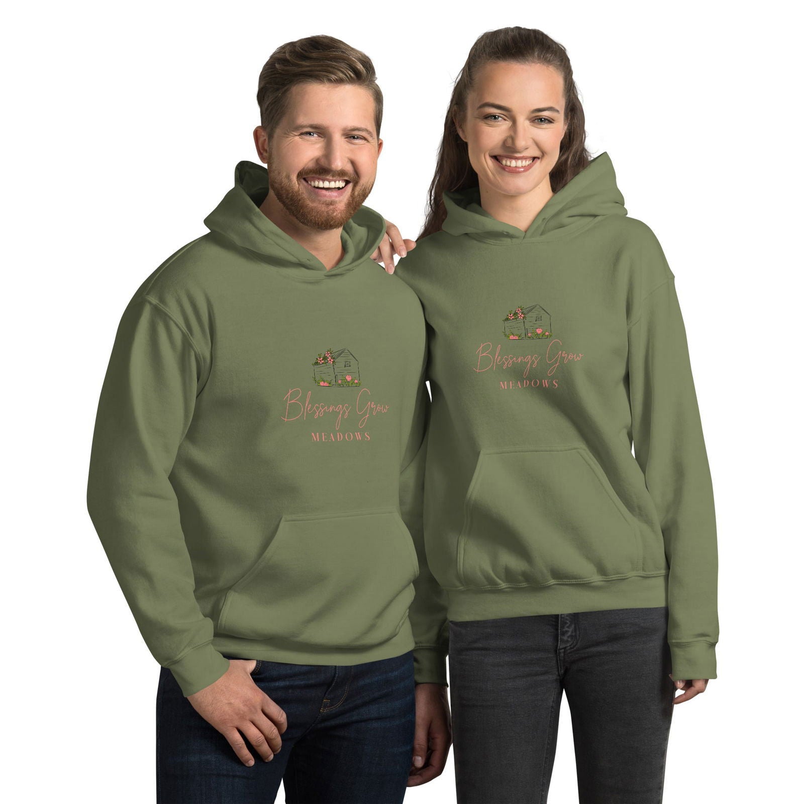 Apparel graphic design featuring a couple modeling olive green hoodies with a Blessings Grow Meadows logo depicting a charming cottage adorned with peach-colored flowers and greenery against a muted green backdrop

