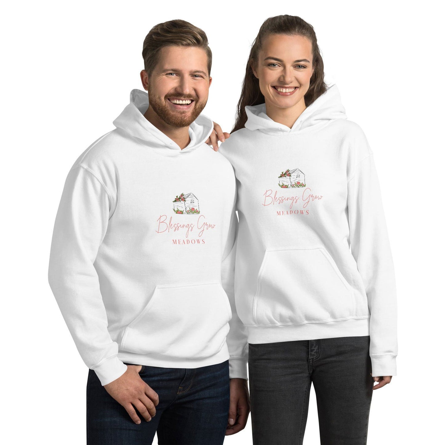 Apparel graphic design featuring a white hoodie with a charming illustration of a house adorned with pink flowers and greenery, showcasing the text Blessings Grow Meadows in a delicate script.
