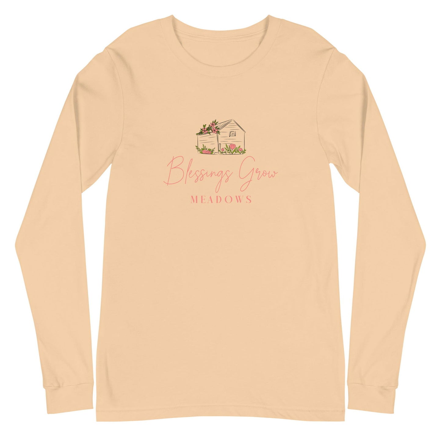 Blessings Grow Meadows long sleeve shirt features a peach-colored tee with a charming illustration of a small house adorned with pink flowers and tulips a light beige-colored house and the brand name in pink script
