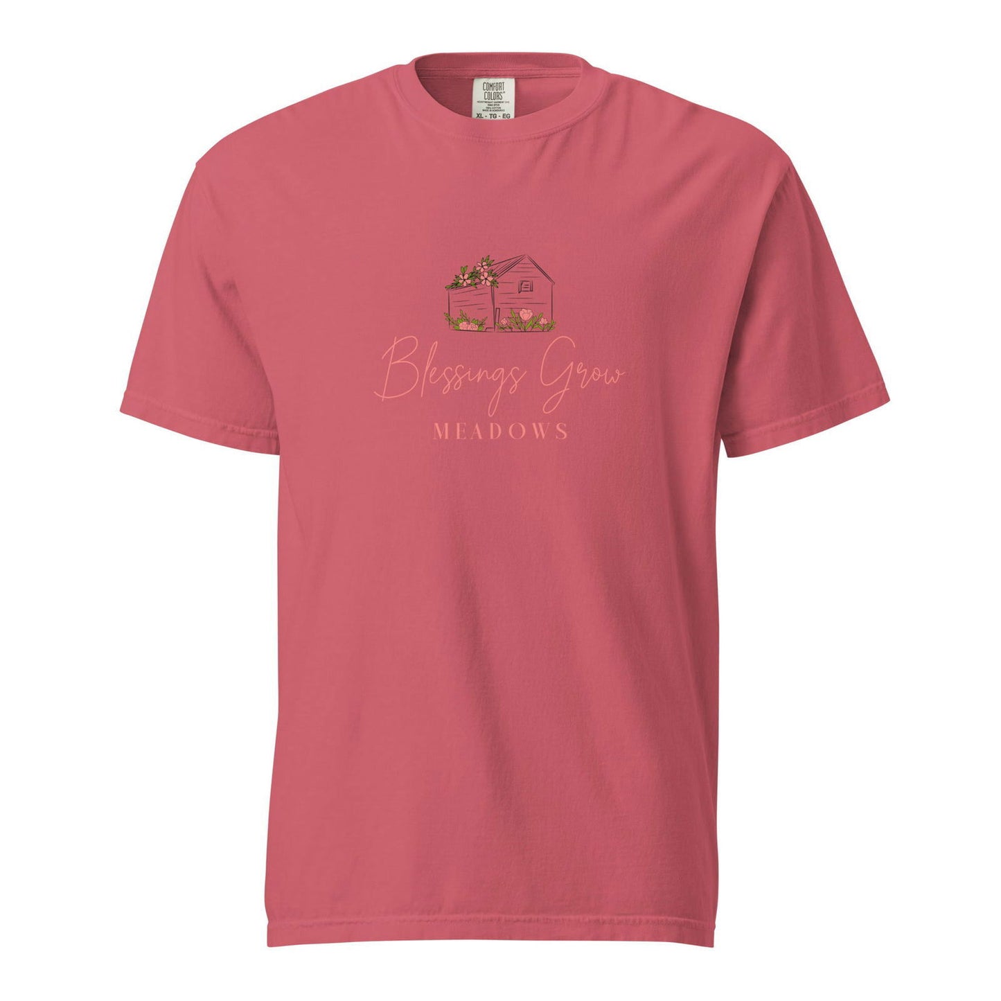 Comfort Colors t-shirt featuring a charming illustration of a cozy house nestled in Meadows with pink flowers,  green grass, and a warm coral color palette
