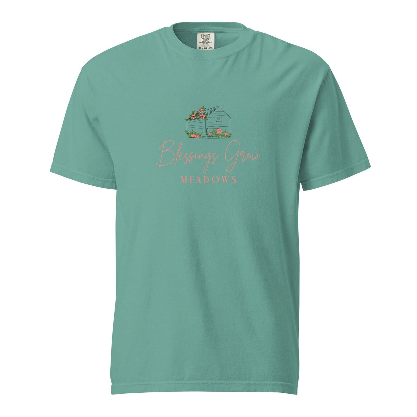 Comfort Colors t-shirt design shows a teal house with pink flowers in a meadow featuring the text Blessings Grow Meadows