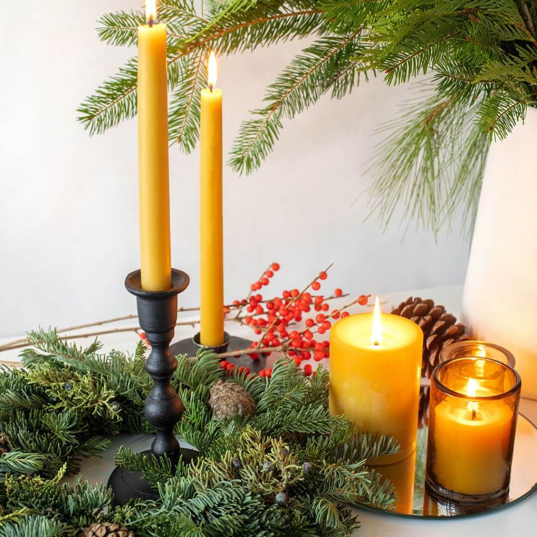 Bluecorn Candles hand-dipped beeswax taper candles in a bulk 4-pair bundle, shown in a natural setting with candle holders.