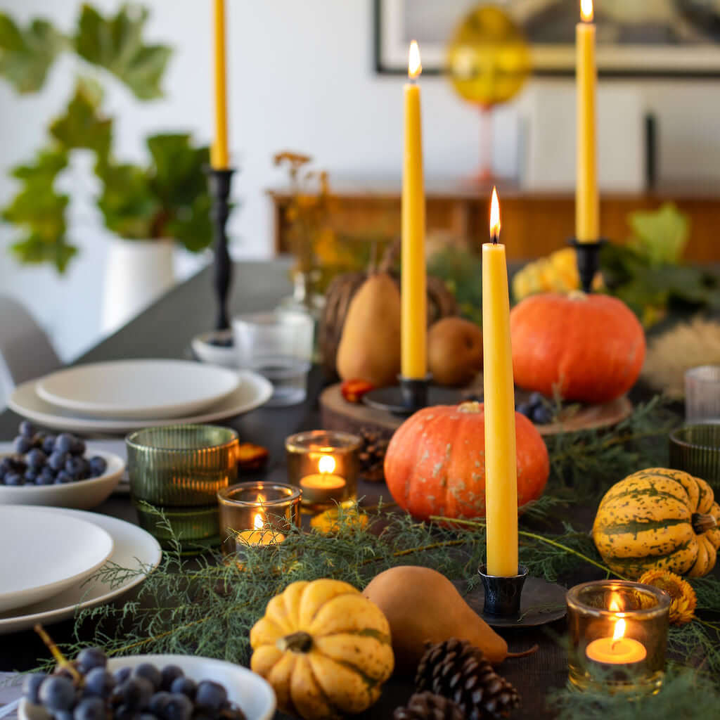 Hand-dipped beeswax taper candles by Bluecorn Candles displayed on a Thanksgiving table with tea light candles.