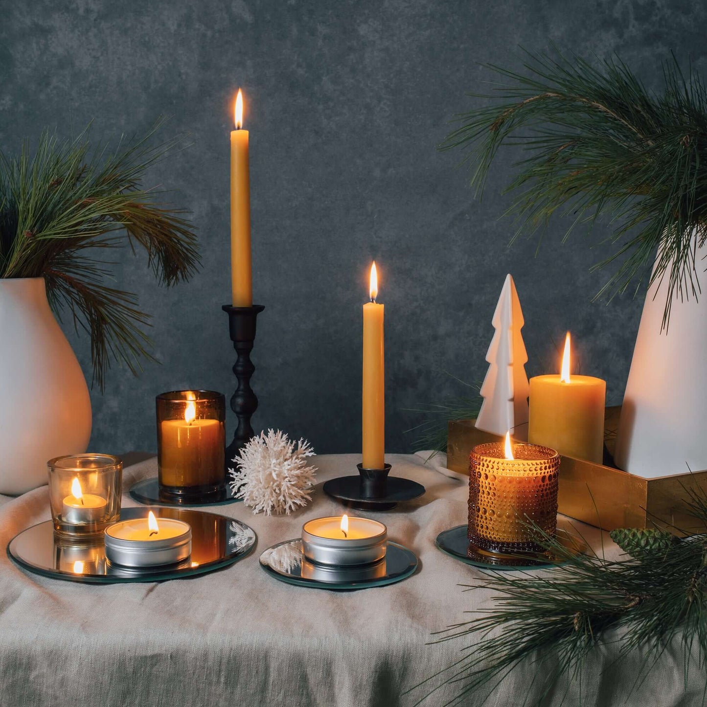 Pair of Bluecorn Candles hand-dipped beeswax taper candles in a natural yellow color, displayed with glass holders on a festive setting.