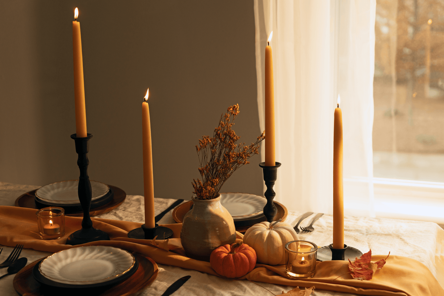 Pair of Bluecorn Candles hand-dipped beeswax taper candles in natural yellow, shown with tea lights for Thanksgiving decor.
