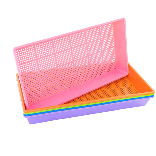 Plastic trays in pink orange purple and green showing gridded bottoms stacked against a white background
