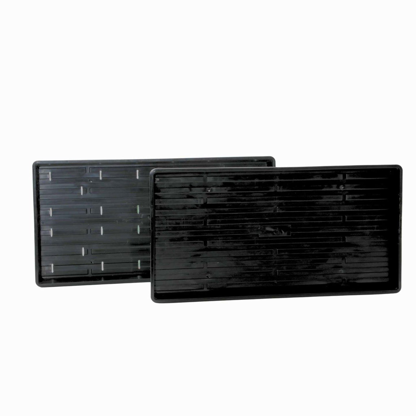 Plastic trays showing a ribbed texture and small drainage holes against a white background

