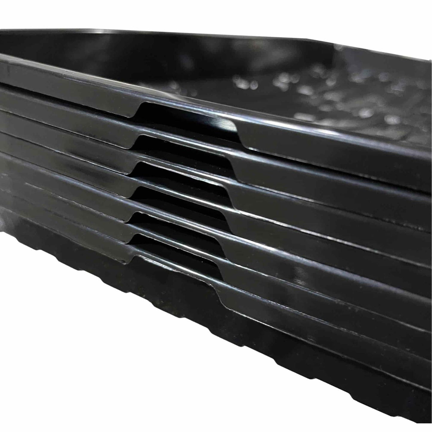 Plastic trays stacked showing glossy black surfaces and unique interlocking edges creating a visually interesting pattern