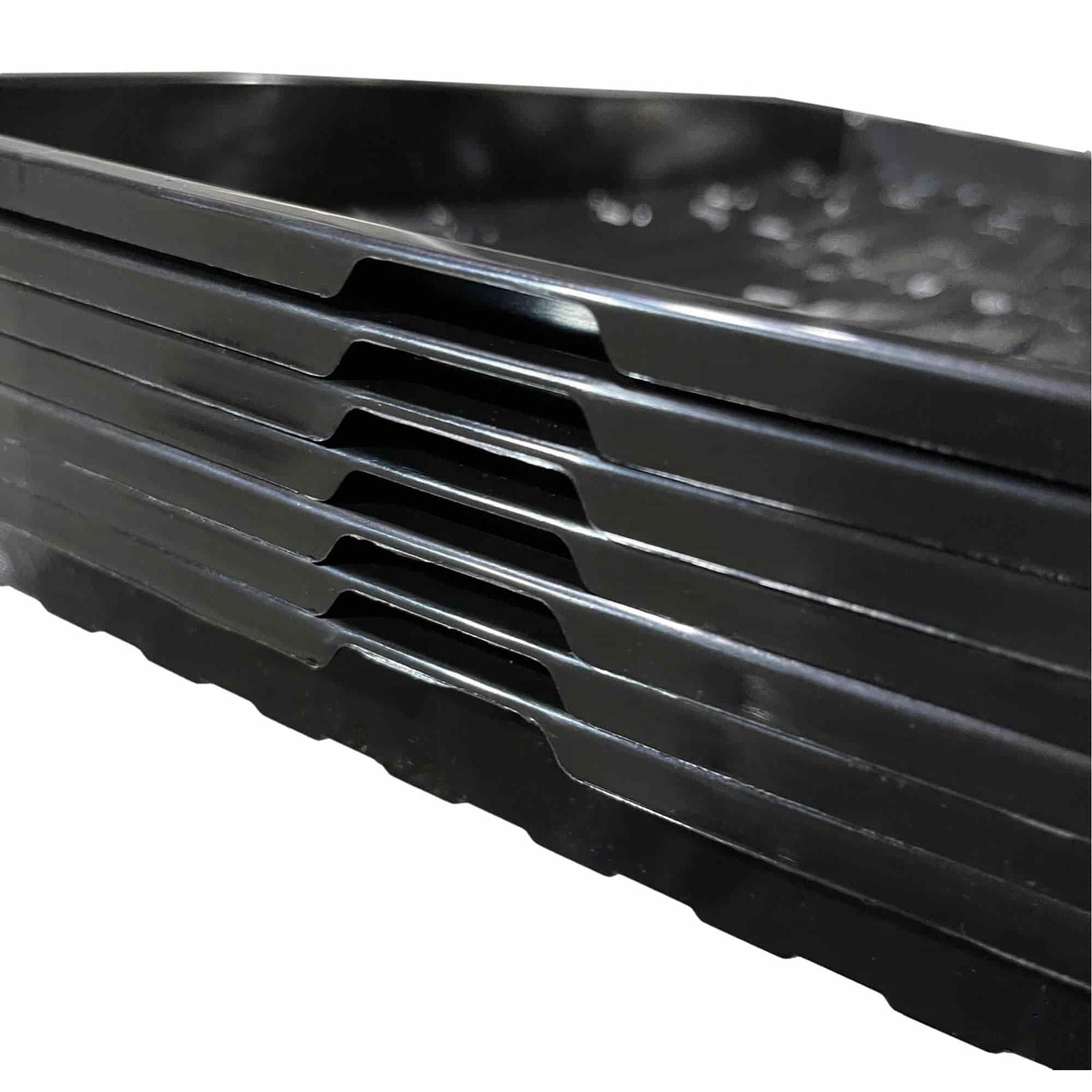 Plastic trays stacked showing glossy black surfaces and unique interlocking edges creating a visually interesting pattern