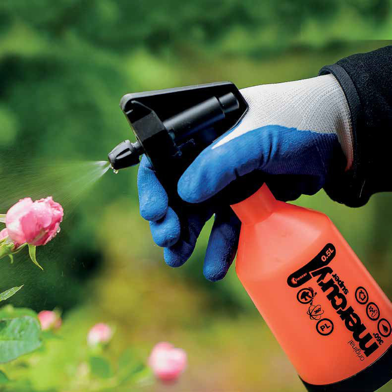 A gloved hand uses the Kwazar Mercury Trigger Sprayer by Bootstrap Farmer to mist water on a pink rosebud. The blurred garden background with lush greenery showcases how the durable double-action sprayer brings life to every petal.
