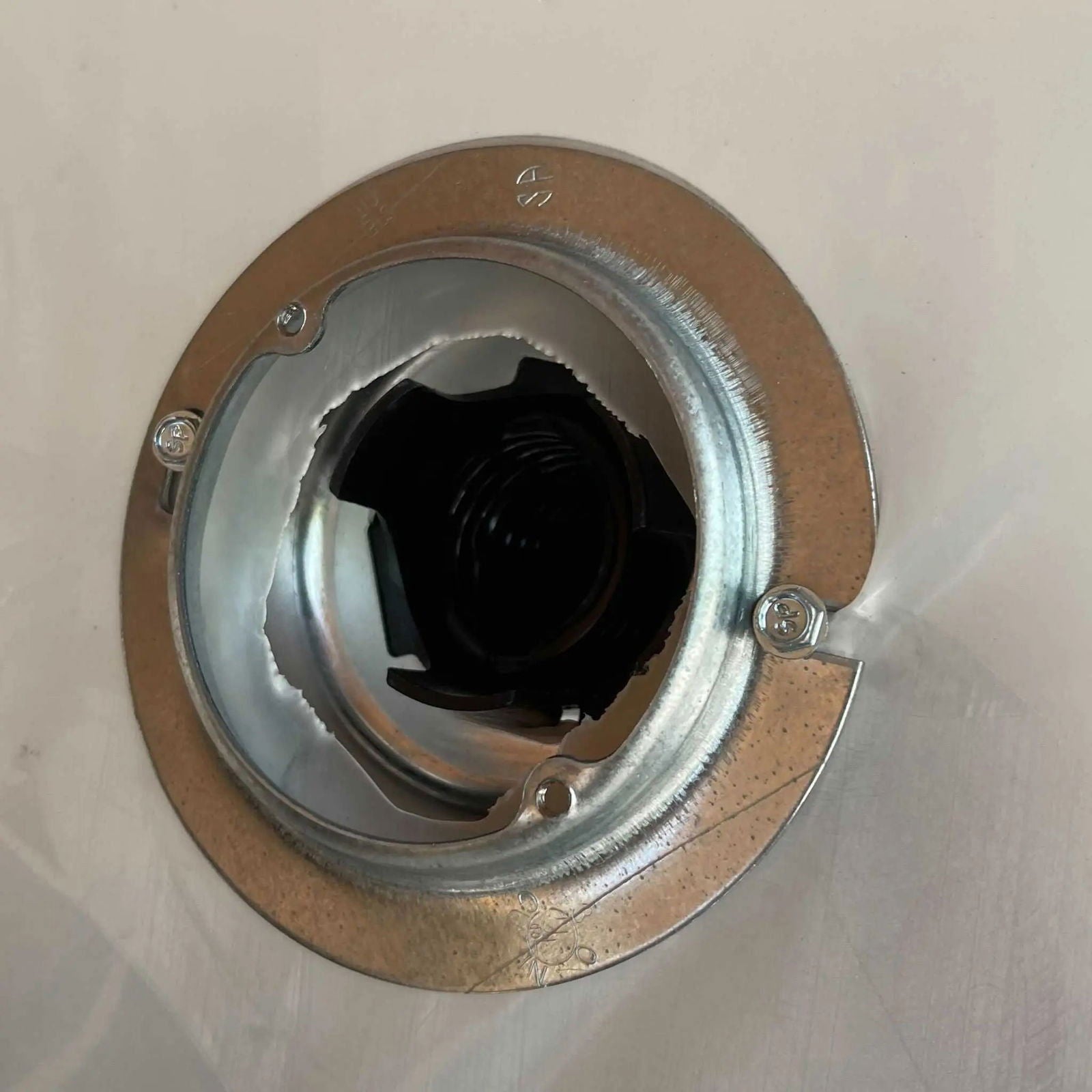 A close-up shows a metal recessed light housing with a round trim and three screws on a white ceiling, designed to limit condensation—much like the Bootstrap Farmer Greenhouse Air Inflation Kit reduces moisture in greenhouses.