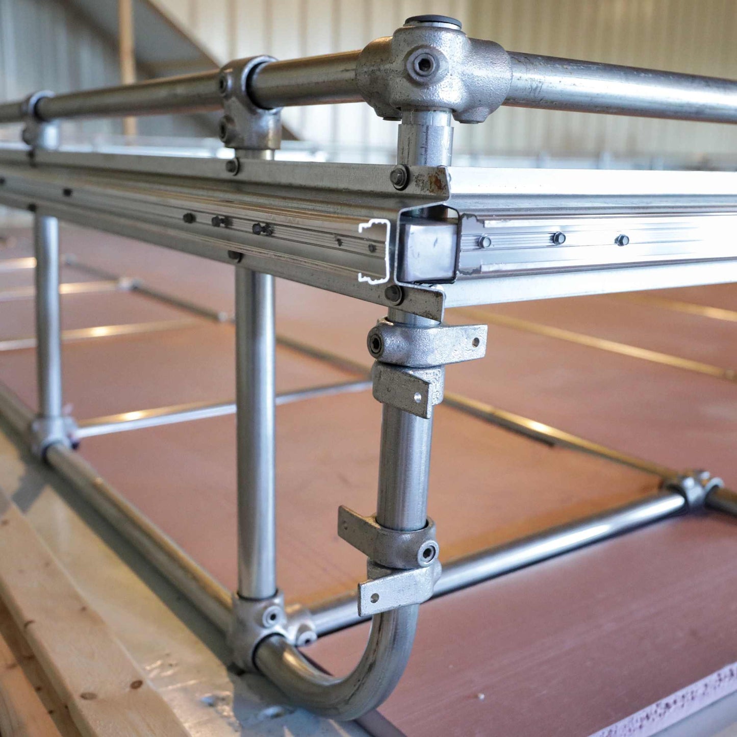 A close-up of a Deep Water Culture (DWC) Kit by Bootstrap Farmer shows its metal frame corner made of interconnected pipes, joints, and brackets. The customizable modular system is set against a beige background, highlighting its industrial design and construction features.