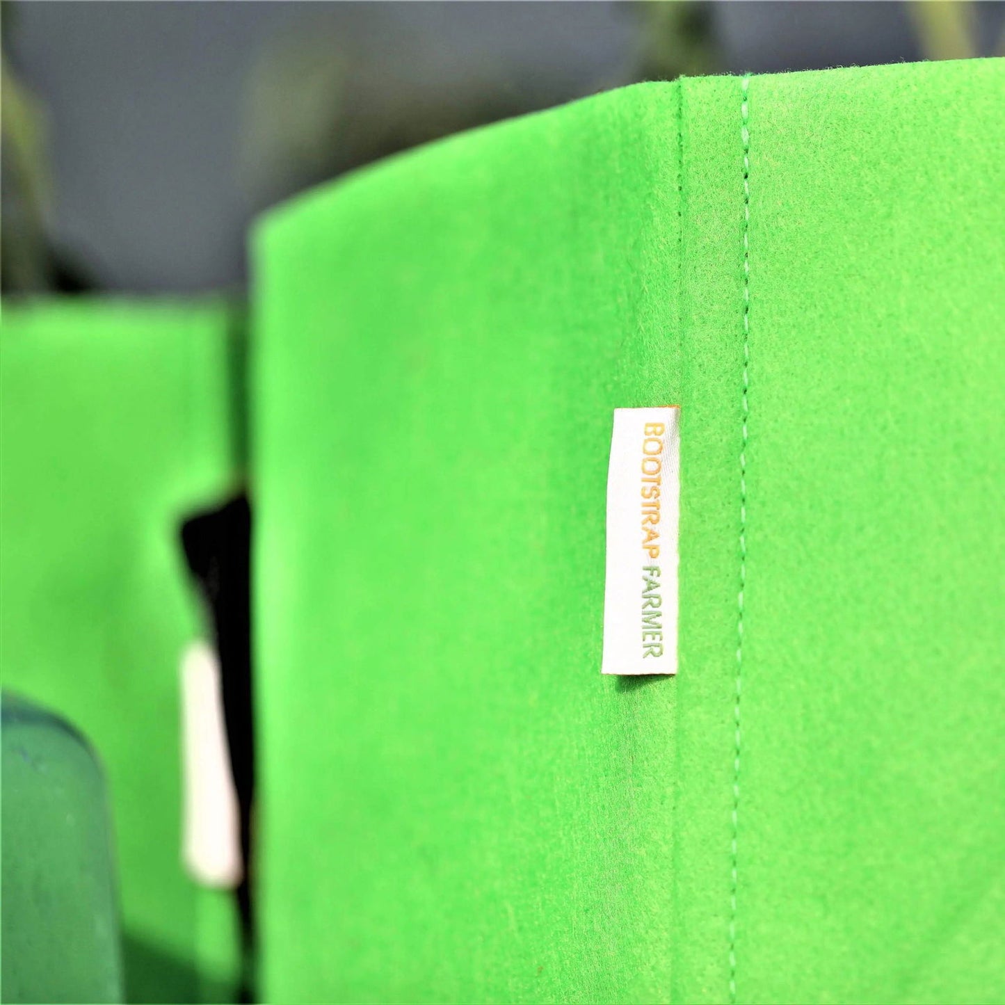 Bootstrap Farmer fabric grow bag showing bright green material and a white label with orange text a close-up product shot
