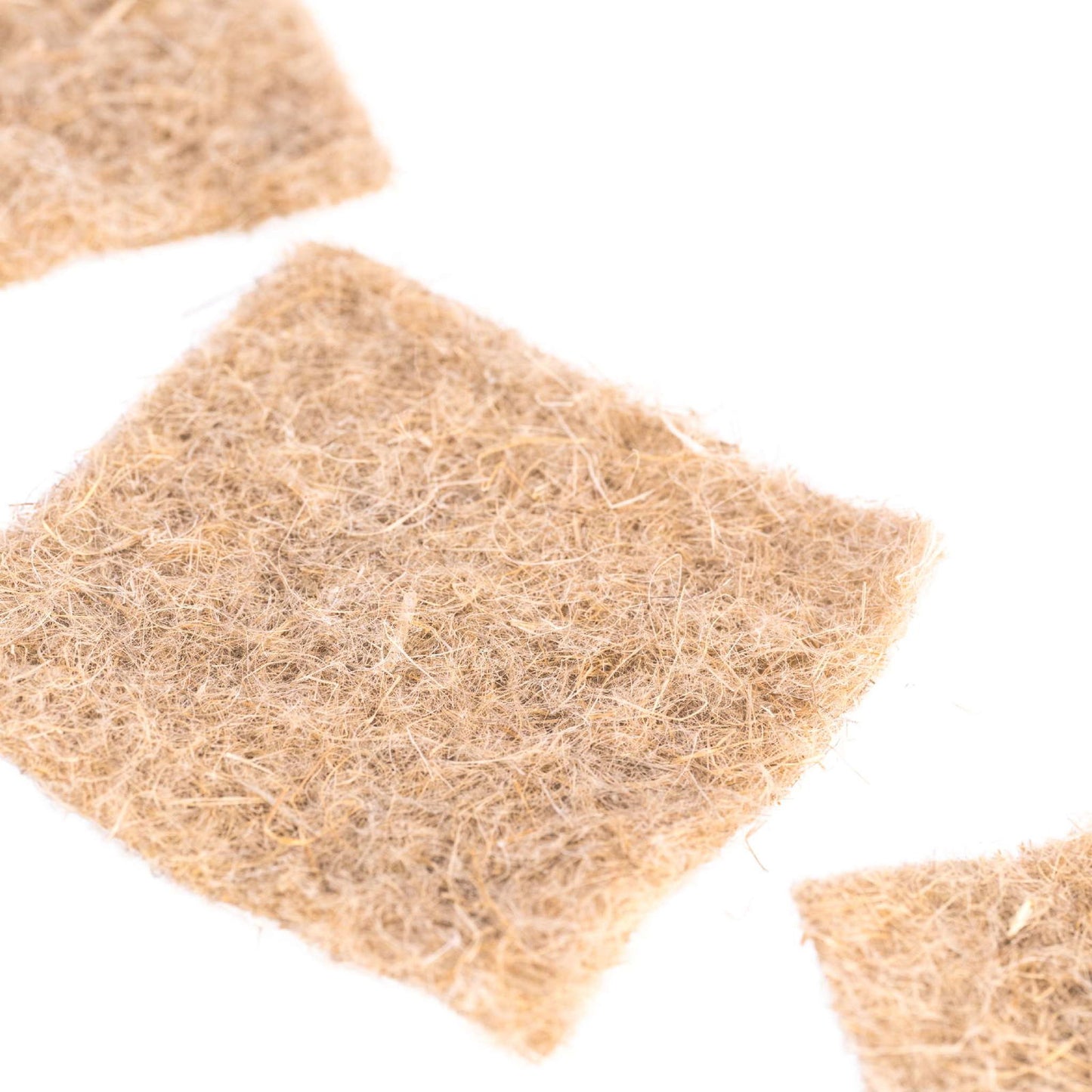 Close-up photo of three pieces of light brown coir fiber mats showing their texture and intricate details of interwoven fibers against a white background