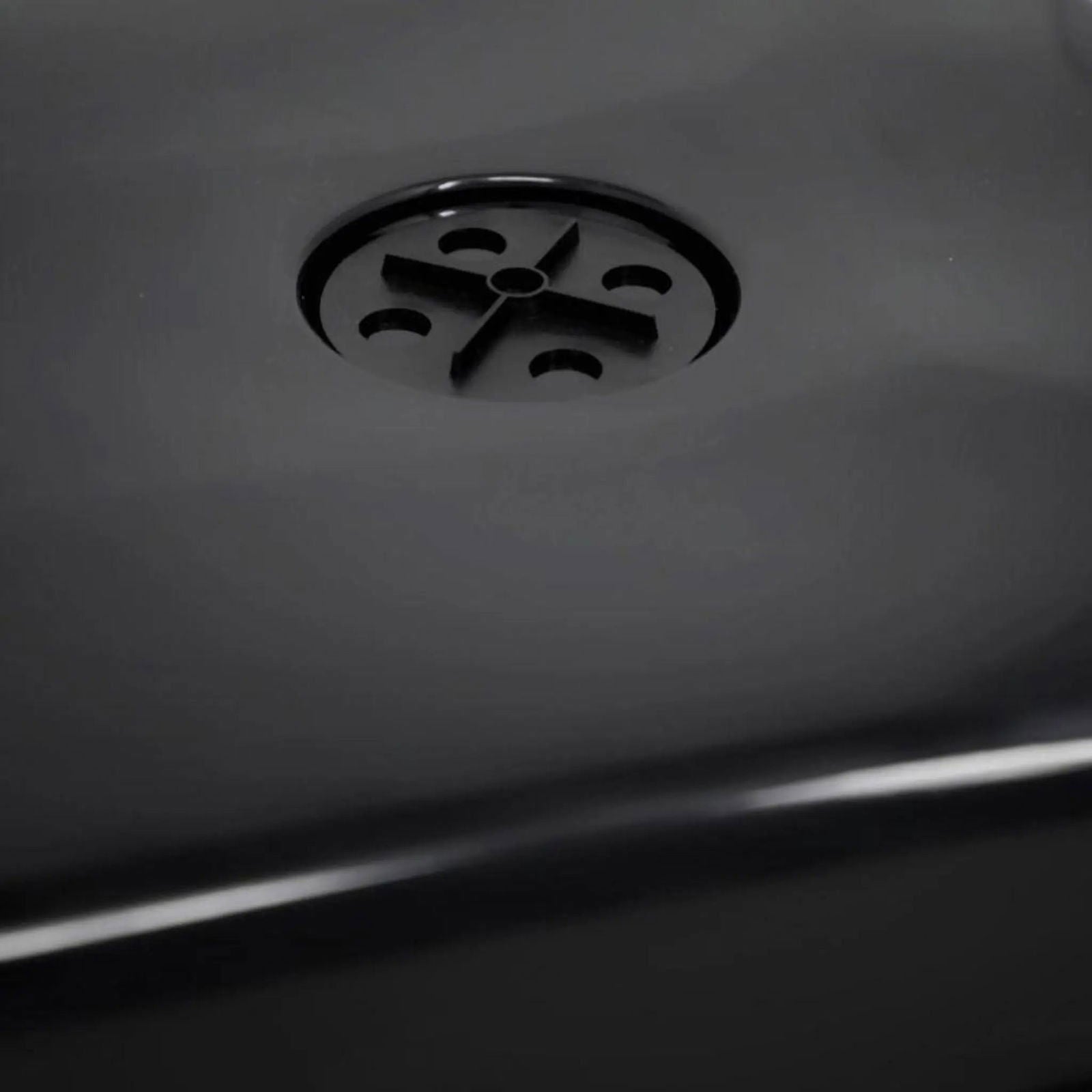 A close-up of a black surface shows a circular drain with a cross-shaped pattern, similar to those in the Bootstrap Farmer 1020 Blackout Humidity Dome used for gardening.