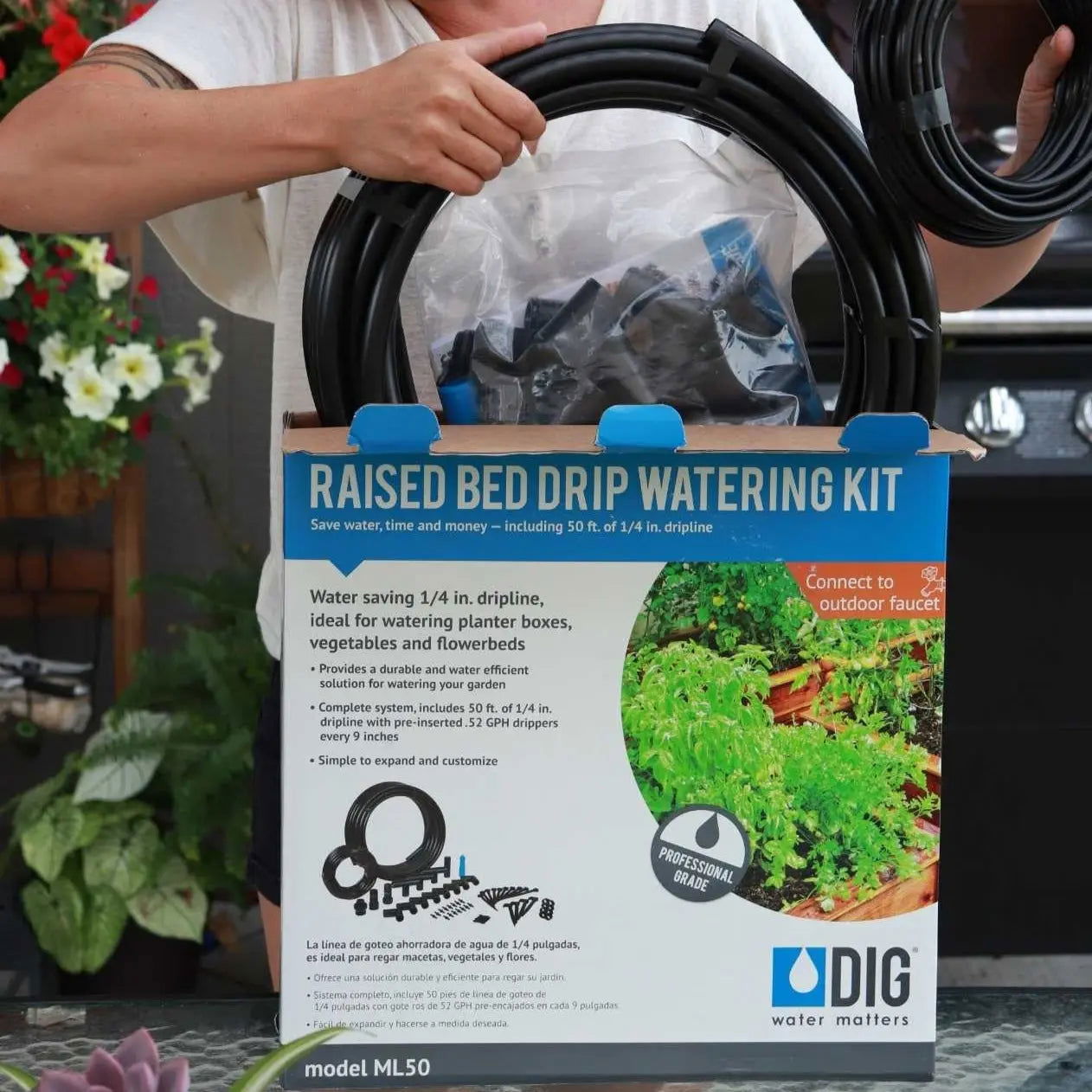 A person holds a boxed Watering - Raised Bed Drip Irrigation Kit by Bootstrap Farmer. The package shows a coiled hose, fittings, and images of lush plants, emphasizing its use for efficient planter box irrigation.