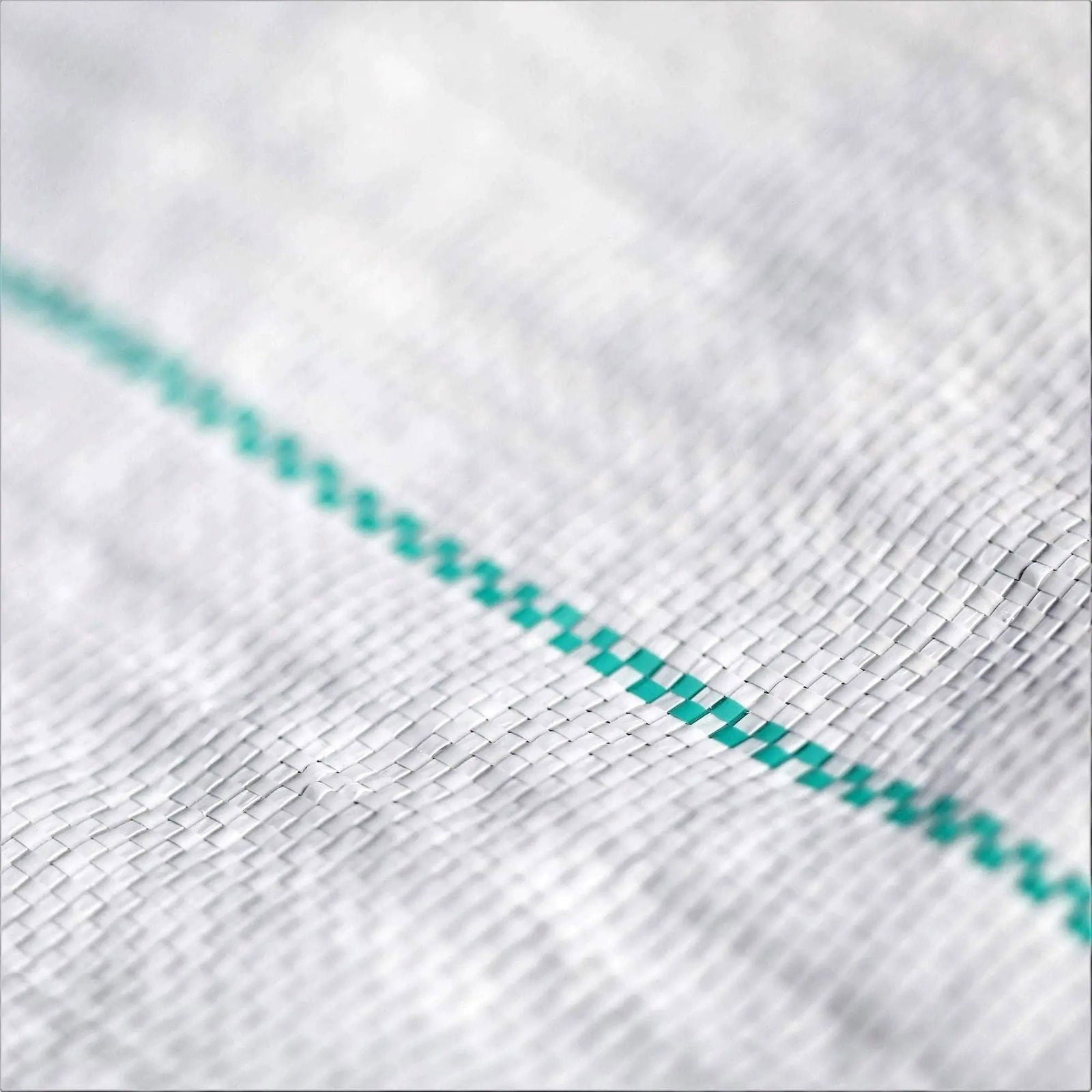 Close-up photograph of a woven fabric texture showing a detailed view of a white mesh with a teal-colored stitched line creating a grid pattern