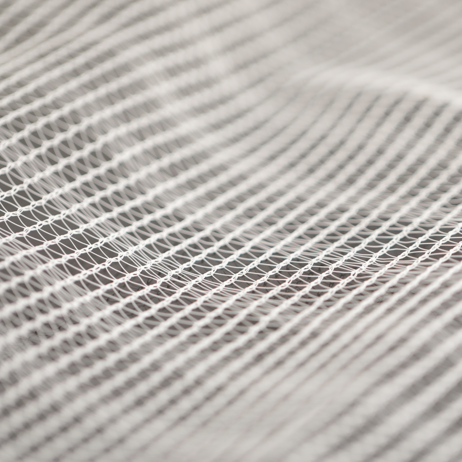 Close-up photograph of a textured white net showing its intricate knotting and subtle shadows