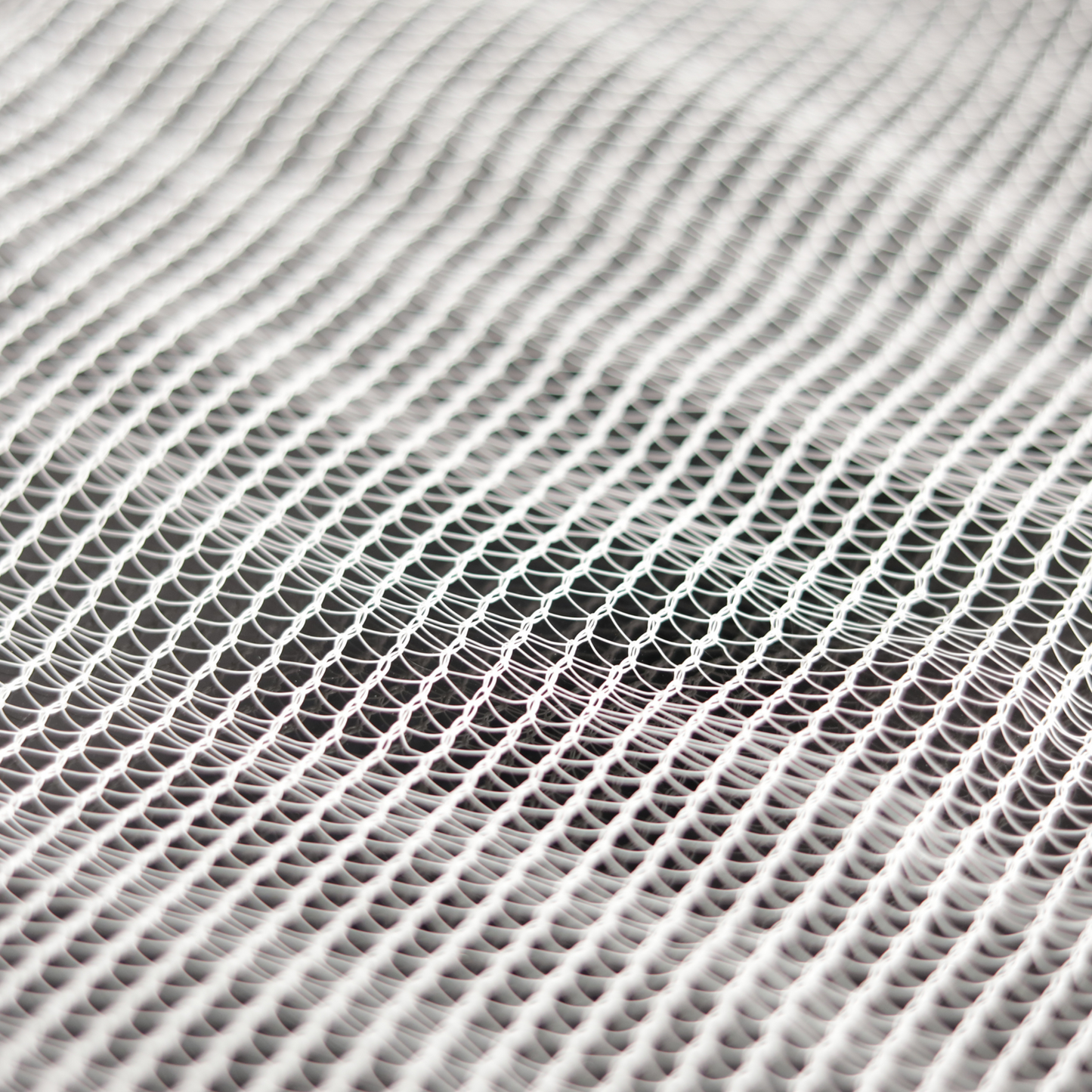Abstract textile artwork depicting a white net-like fabric with a subtle wave pattern showing delicate interlacing and varying shades of gray and white.
