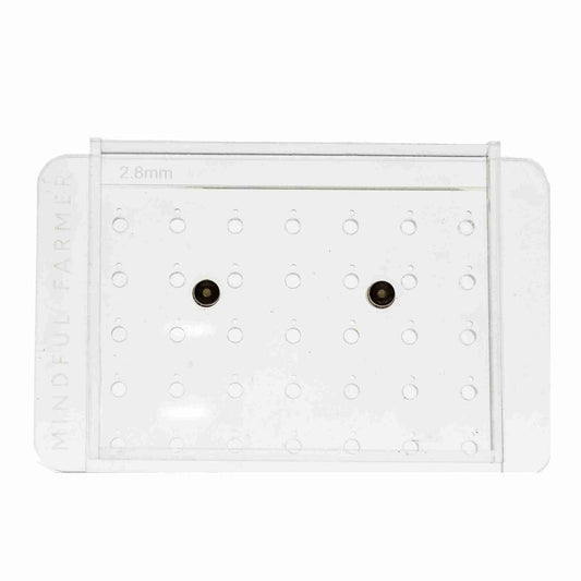 The Bootstrap Farmer Soil Block Drop Seeder - Standing 35 - Complete Set features a transparent, precision-cut acrylic design with two metal inserts and "MINDFUL FARMER" and "2.8mm" engraved for accurate seed placement.