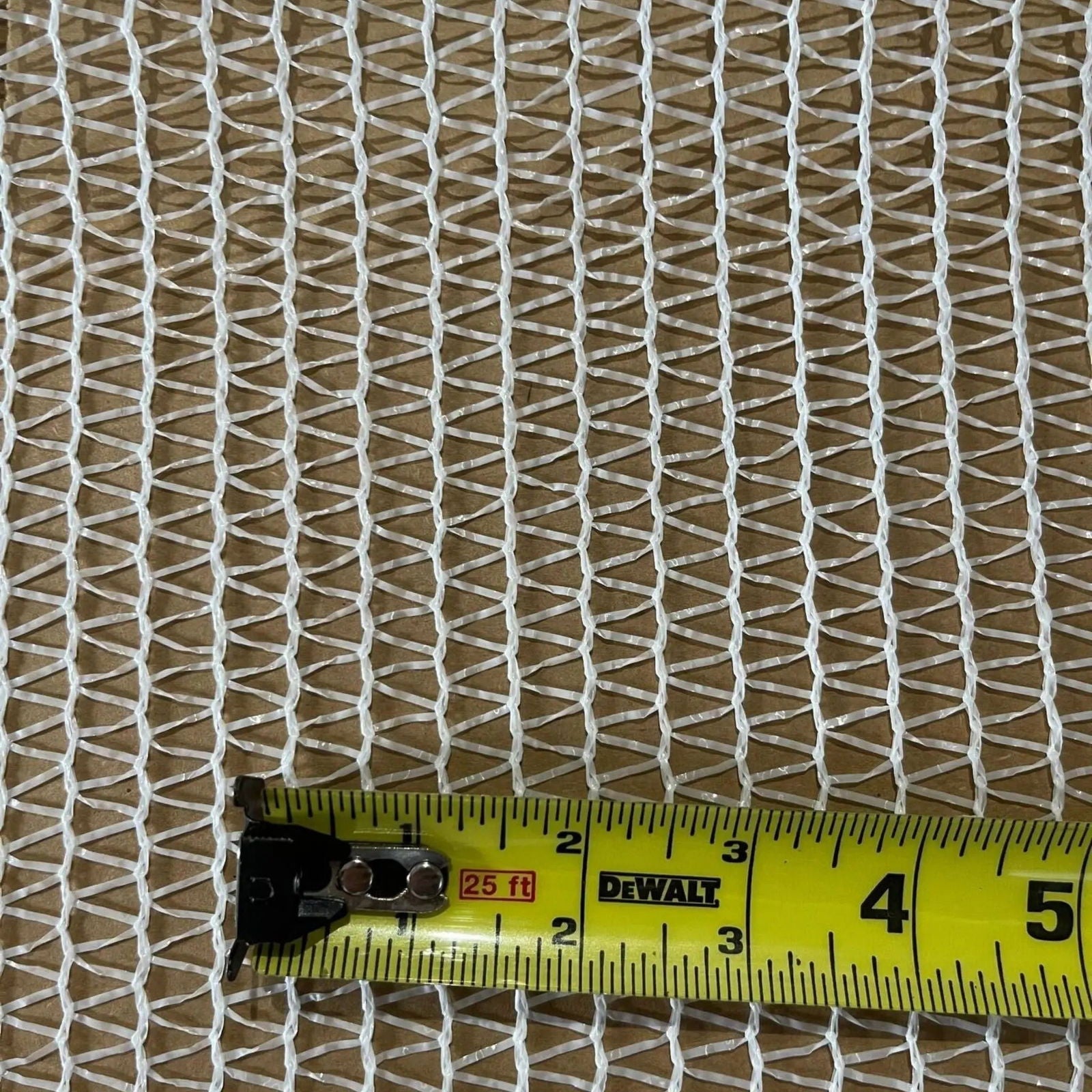 A close-up image shows the Bootstrap Farmer Greenhouse Shade Cloth - 30% White, draped over a brown surface with a yellow measuring tape at the bottom, displaying inches from 3 to 5.