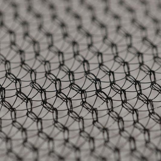 Close-up photograph of a black wire mesh network showing its intricate hexagonal pattern and subtle reflective highlights with a shallow depth of field
