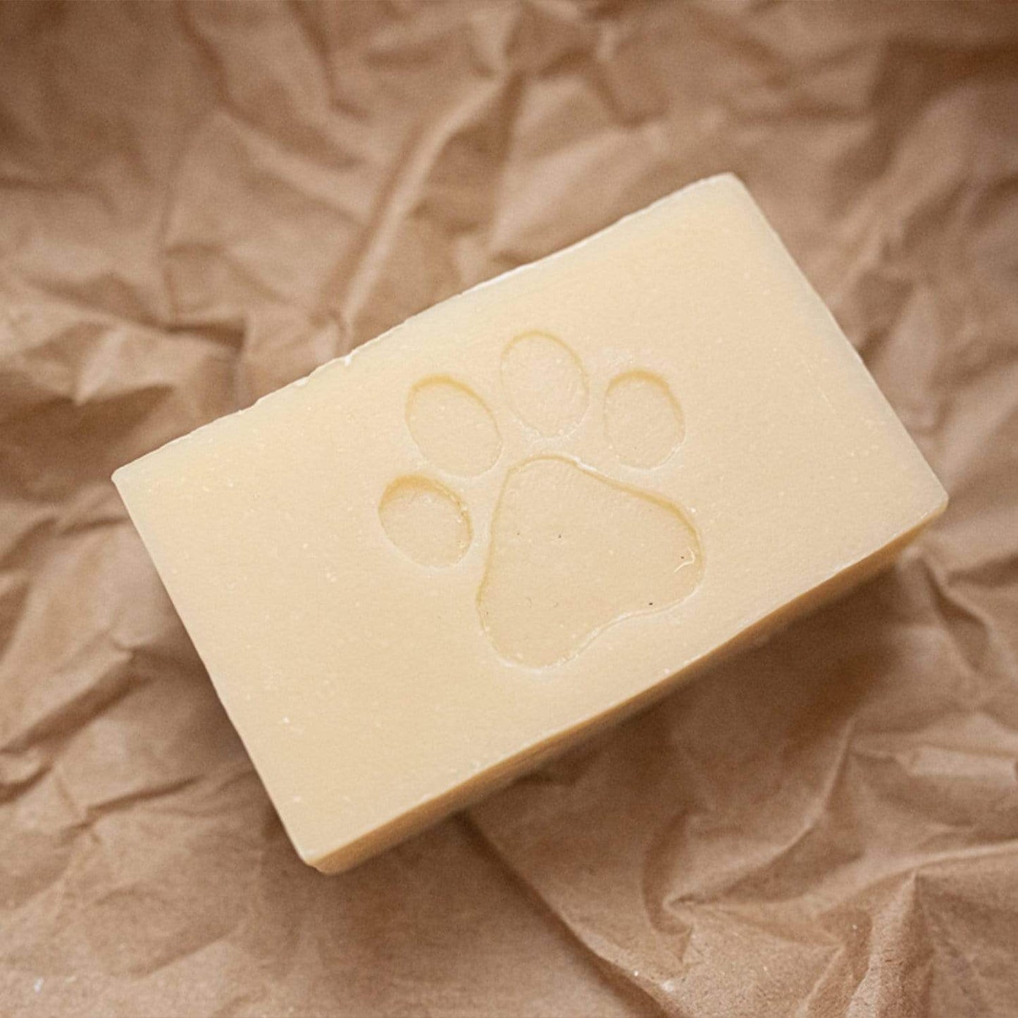 A 4oz rectangular Pet Shampoo Bar by ZeroWasteStore.com, all natural, vegan, and plastic free, featuring a paw print design and displayed on crumpled brown paper.
