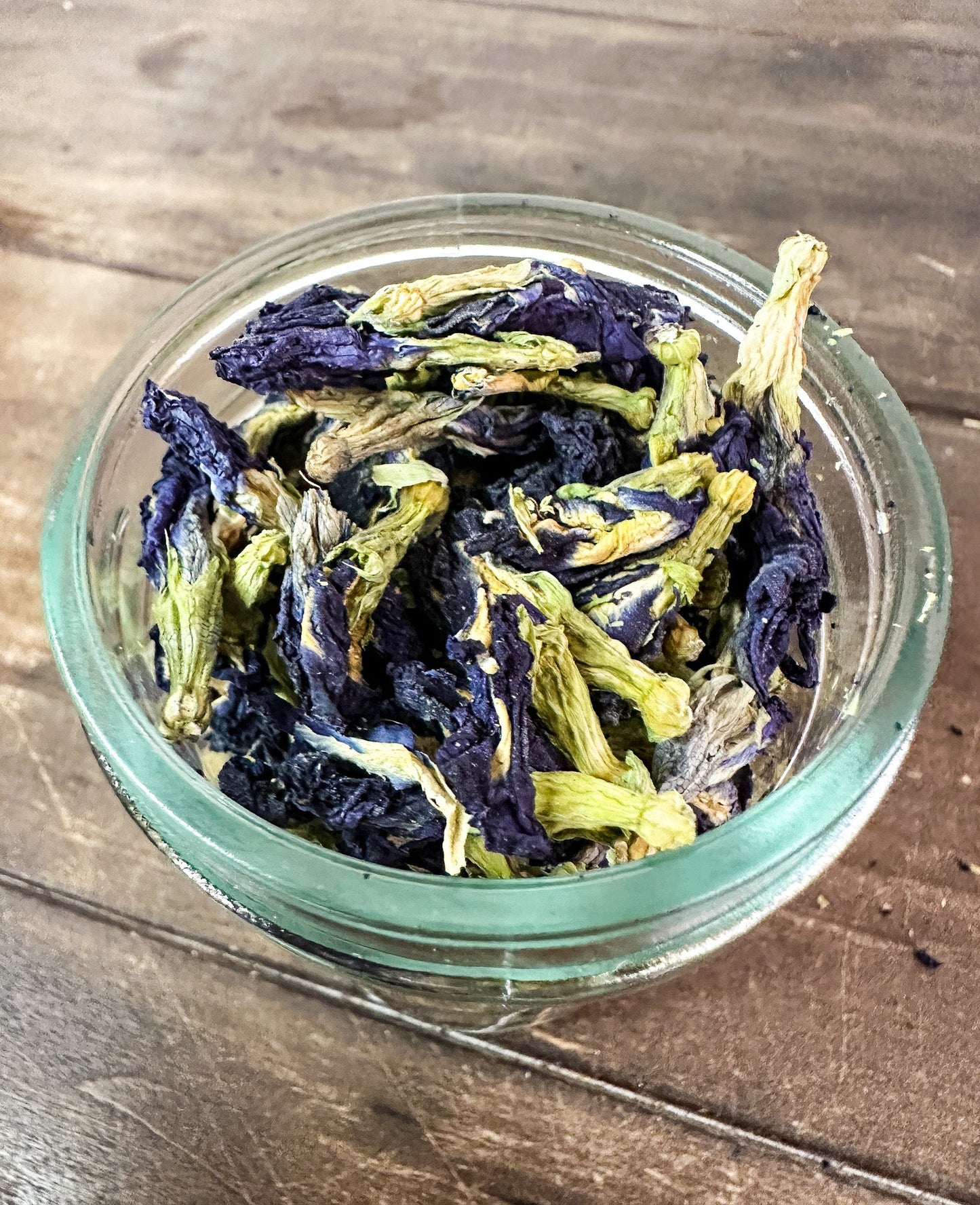 Small jar of dried butterfly pea flowers from herbalroseapothecary herb jars collection, showcasing vibrant blue herbs in a compact container.