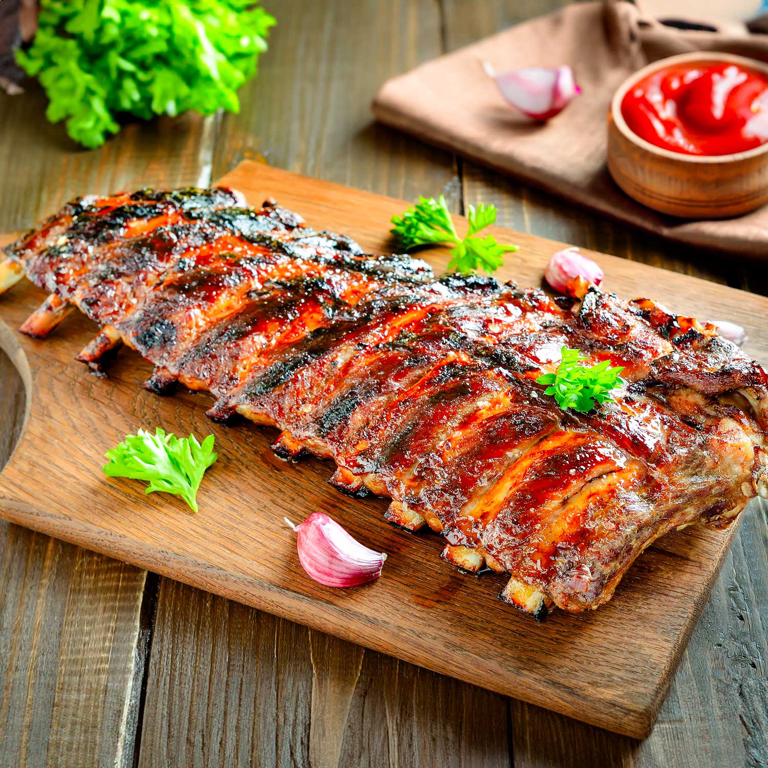 Juicy BBQ ribs with candied orange glaze from Pig of the Month BBQ, shown topped with orange slices and served on a platter.