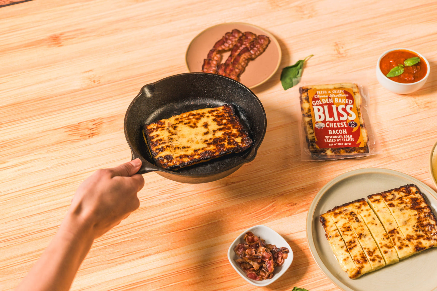 Golden baked Bacon Bliss cheese by Cheese Brothers, Inc., featuring crispy bacon bits in a baked cheese block.