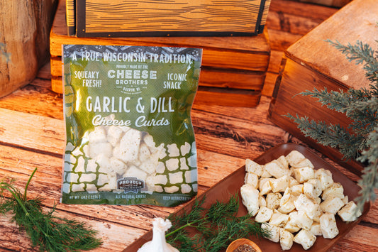Garlic and dill cheese curds by Cheese Brothers, Inc., showing fresh cheese curds with herbs in a clear pack, ready to enjoy.