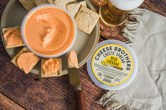 Creamy Beer Cheddar Cheese Spread by Cheese Brothers, Inc. displayed in a jar with a smooth, rich texture and golden color.