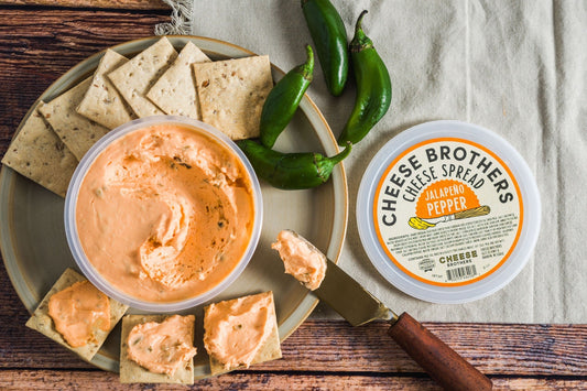 Creamy Jalapeño Pepper Cheese Spread by Cheese Brothers, Inc. served in a jar with visible spicy jalapeño pieces.
