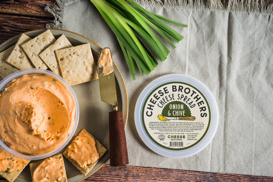 Creamy Onion and Chive Cheese Spread by Cheese Brothers, Inc. in a jar with visible herbs and smooth texture.