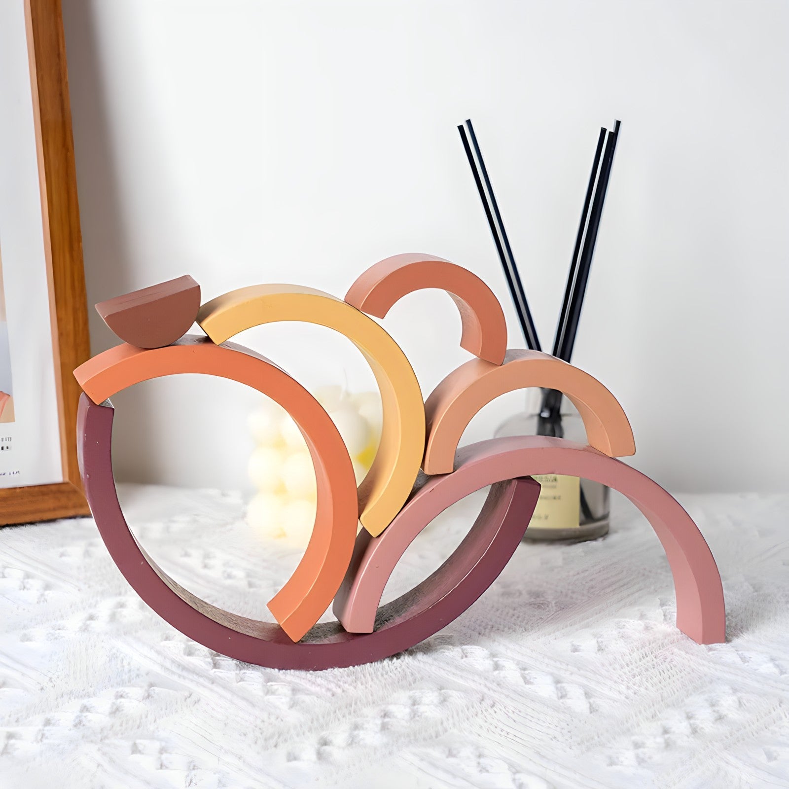 Small wooden rainbow arch blocks by Petite Pioneers arranged in a colorful stack on a white background.