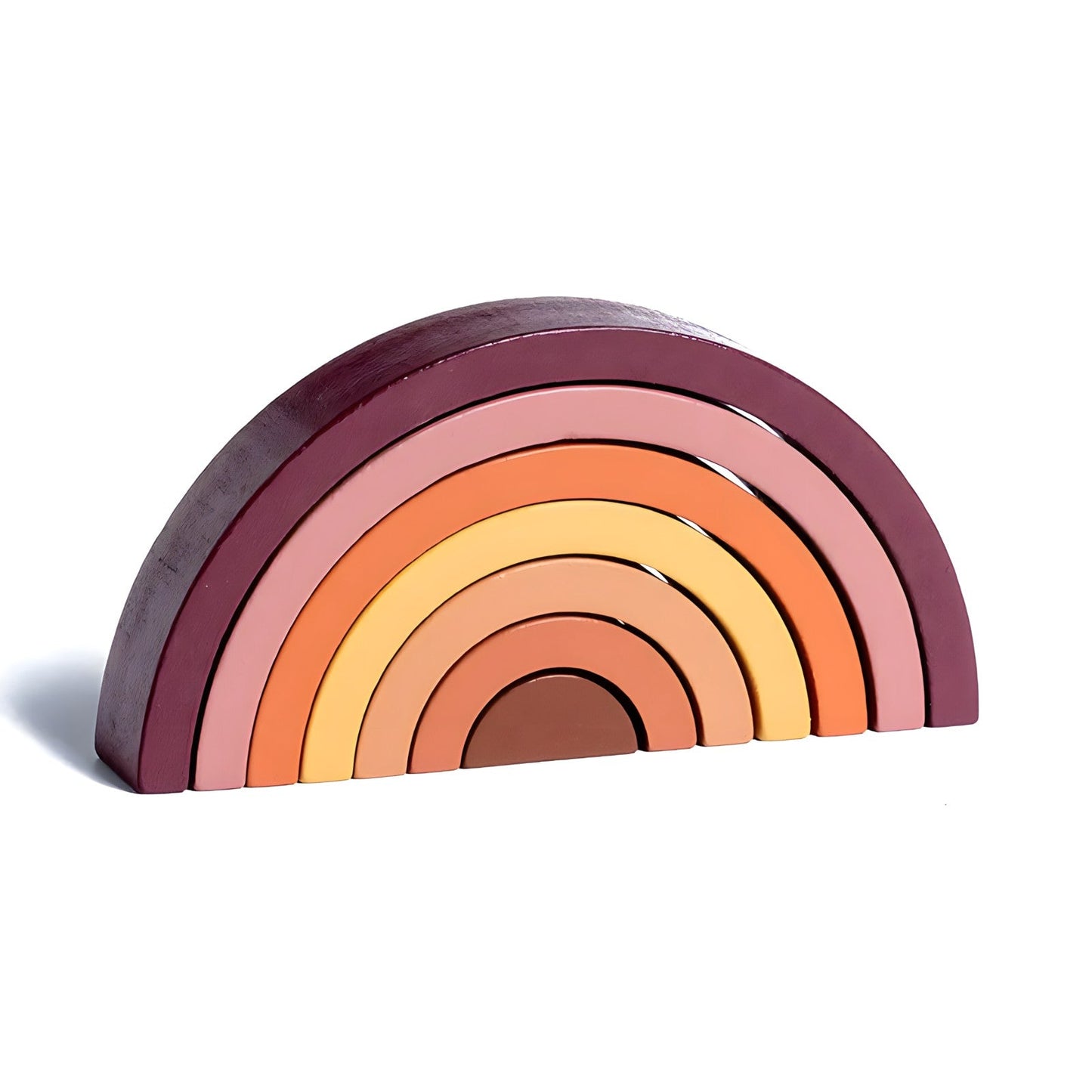 Colorful small wooden rainbow arch blocks by Petite Pioneers arranged in a playful stack on a white background.