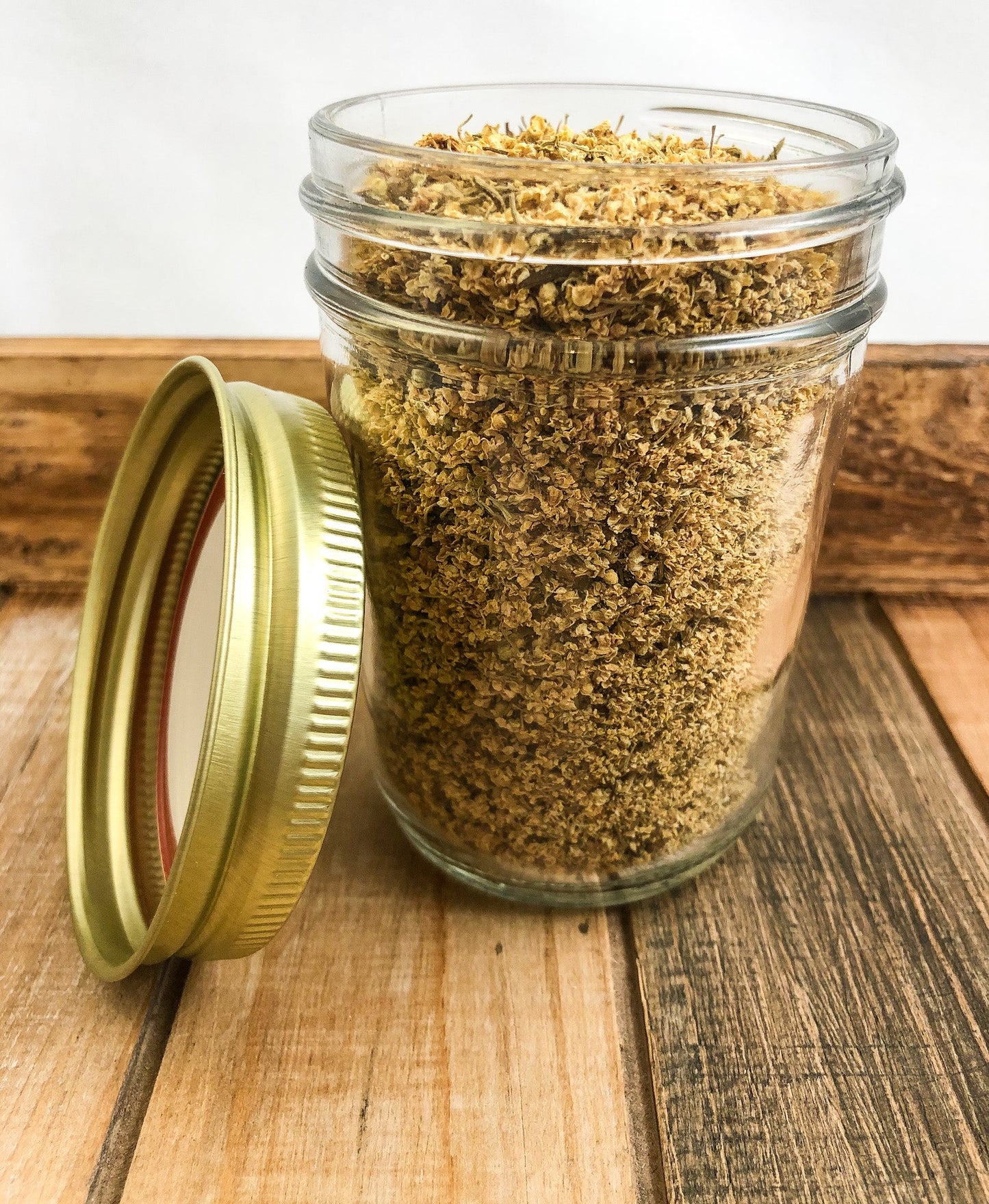 Small jar of dried elderflowers herb from HerbalRoseApothecary, featuring a wood and white ceramic lid.