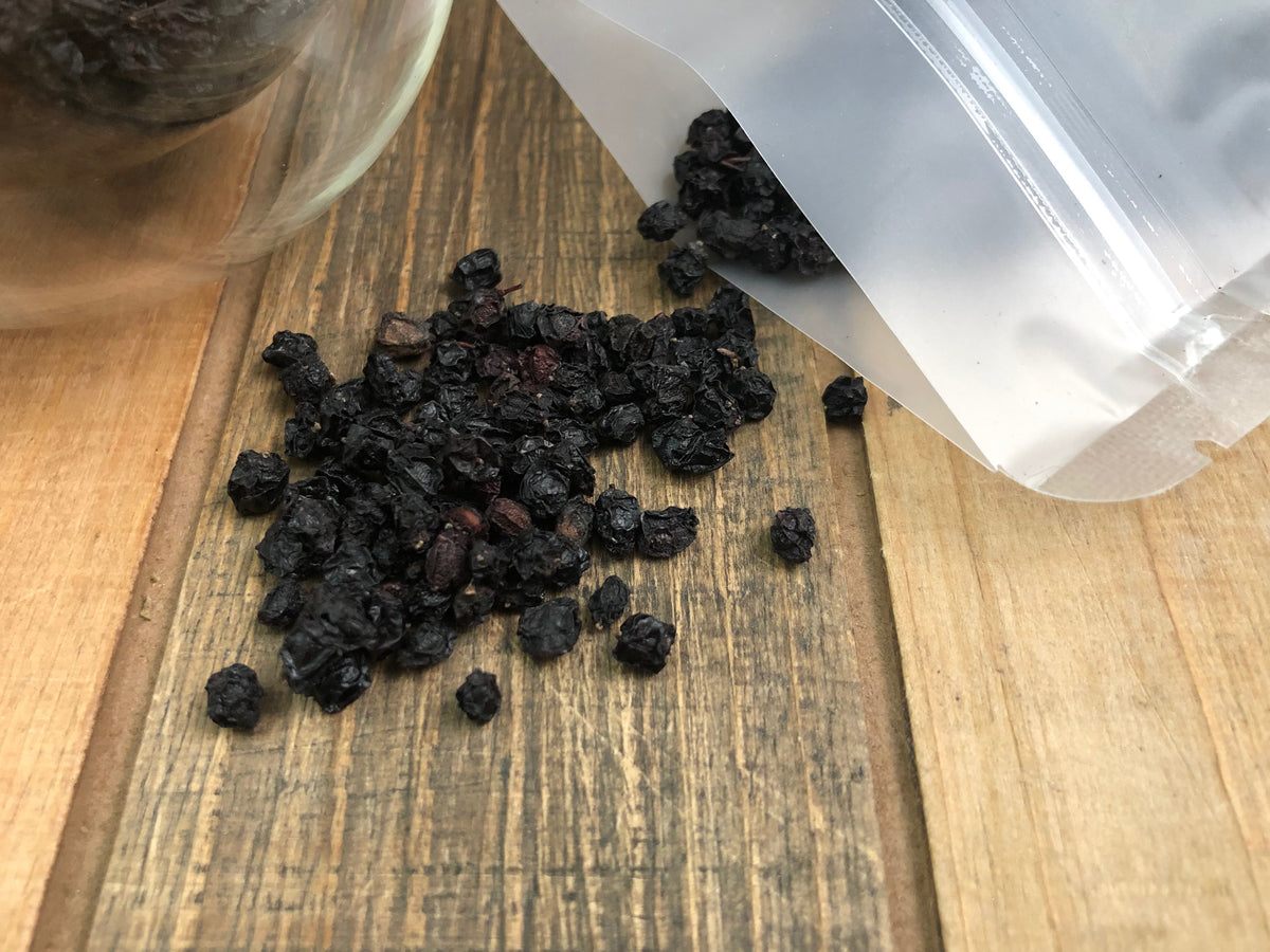 Dried organic elderberries from HerbalRoseApothecary, showcasing a close-up of dark purple elderberries in a natural herbal presentation.