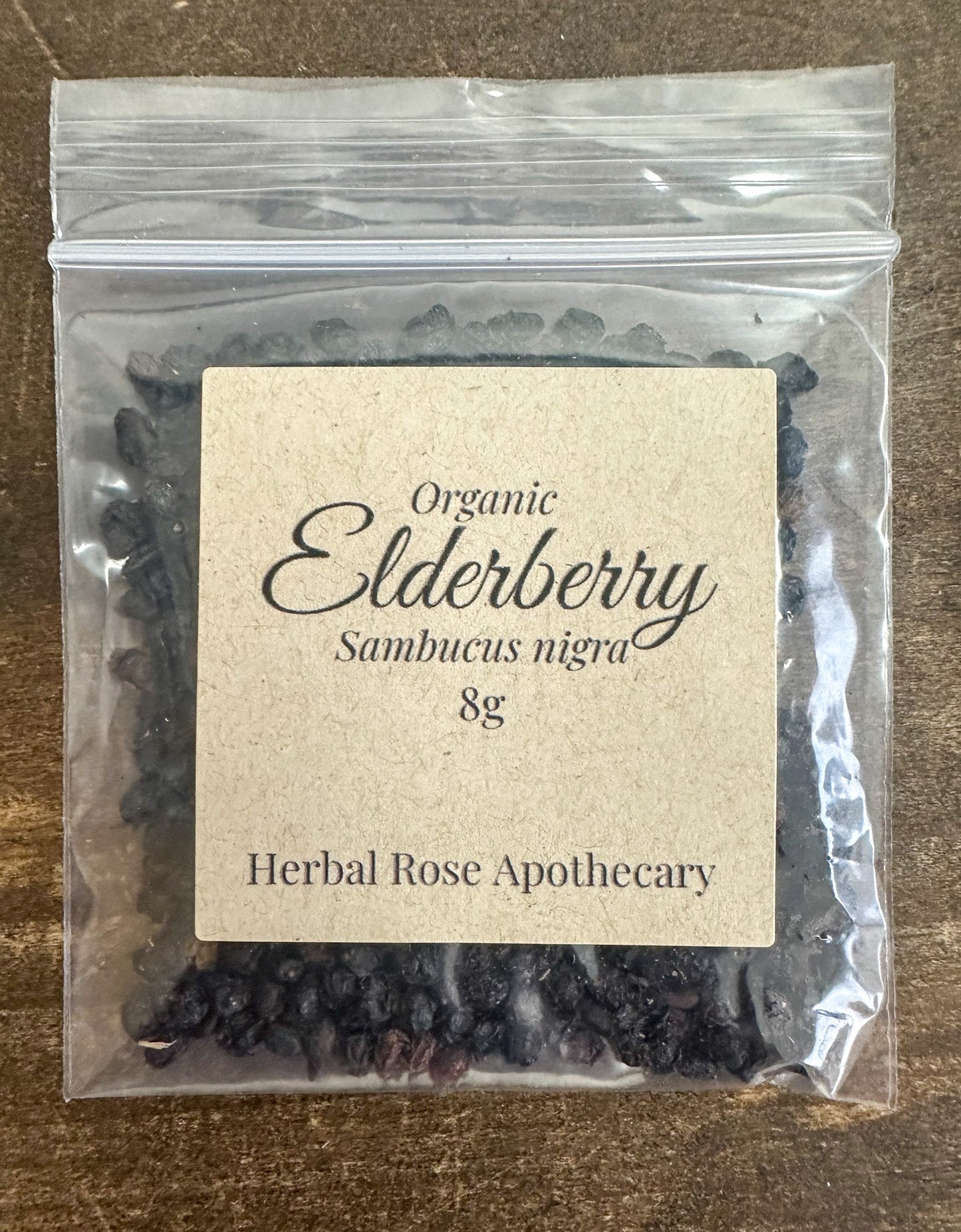Dried organic elderberries from herbalroseapothecary in an 8g package, showing small, dark purple berries suitable for herbal remedies.