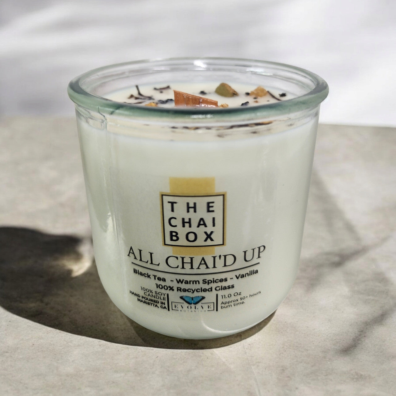 Evolve Botanica Rocks Candle Chai with wood wick and gemstone, soy wax, burning with warm, soothing glow.