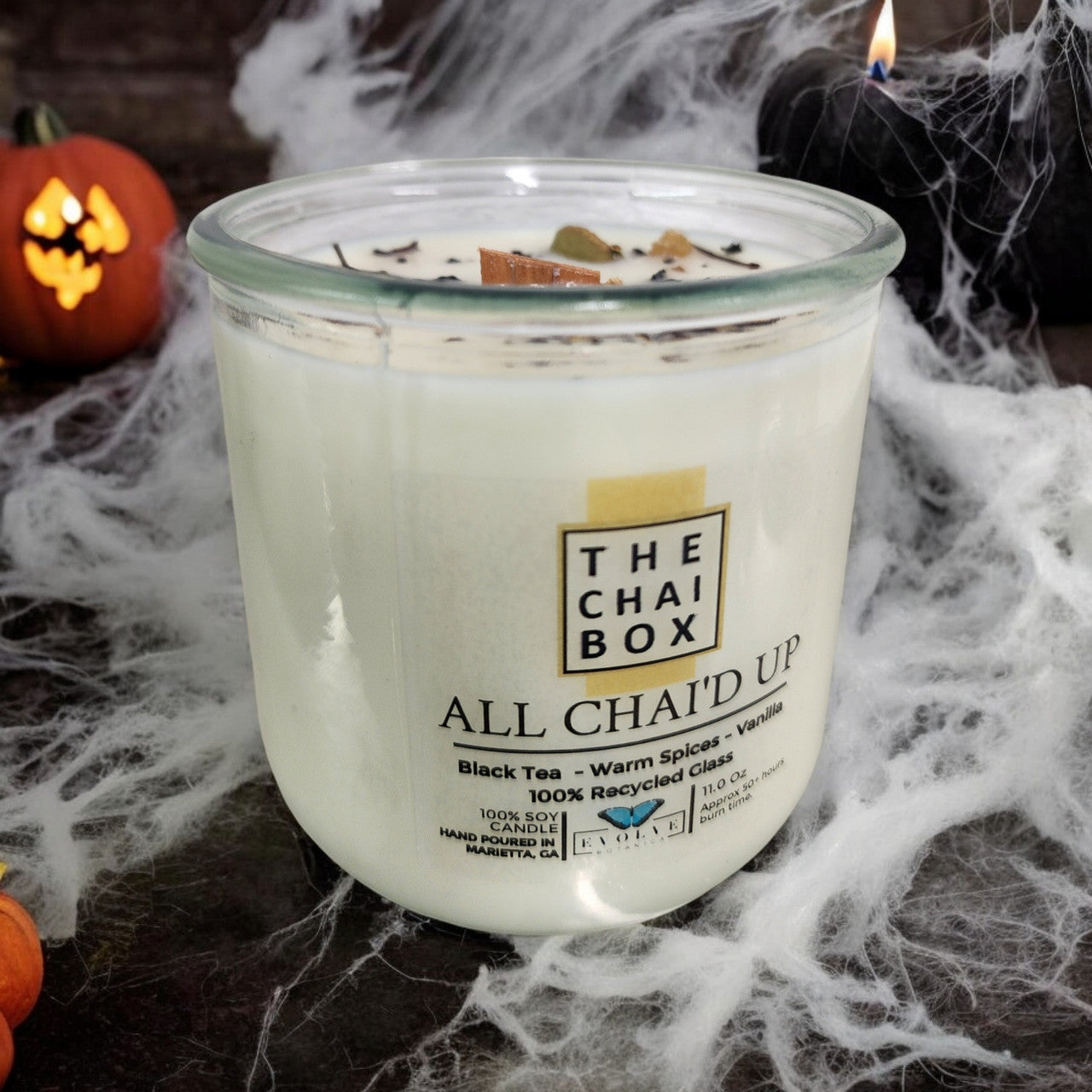 Evolve Botanica Rocks Candle in Chai with wood wick and gemstone accents, soy wax, placed on a wooden surface.