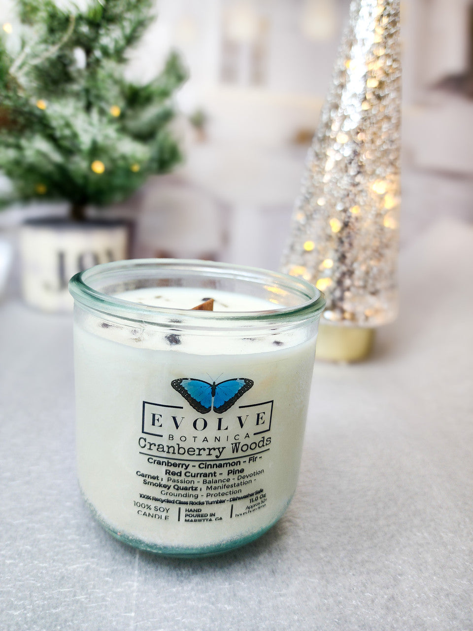 Evolve Botanica Cranberry Woods soy candle with wood wick, garnet and smokey quartz gemstone accents in a decorative glass jar.