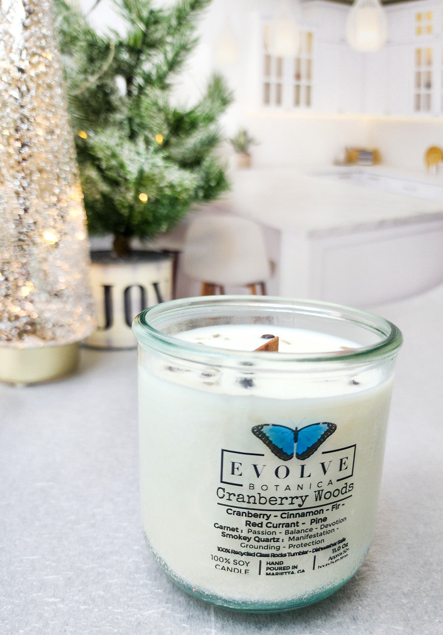 Evolve Botanica Cranberry Woods soy candle with wood wick, garnet and smoky quartz gemstones, set in a decorative jar.