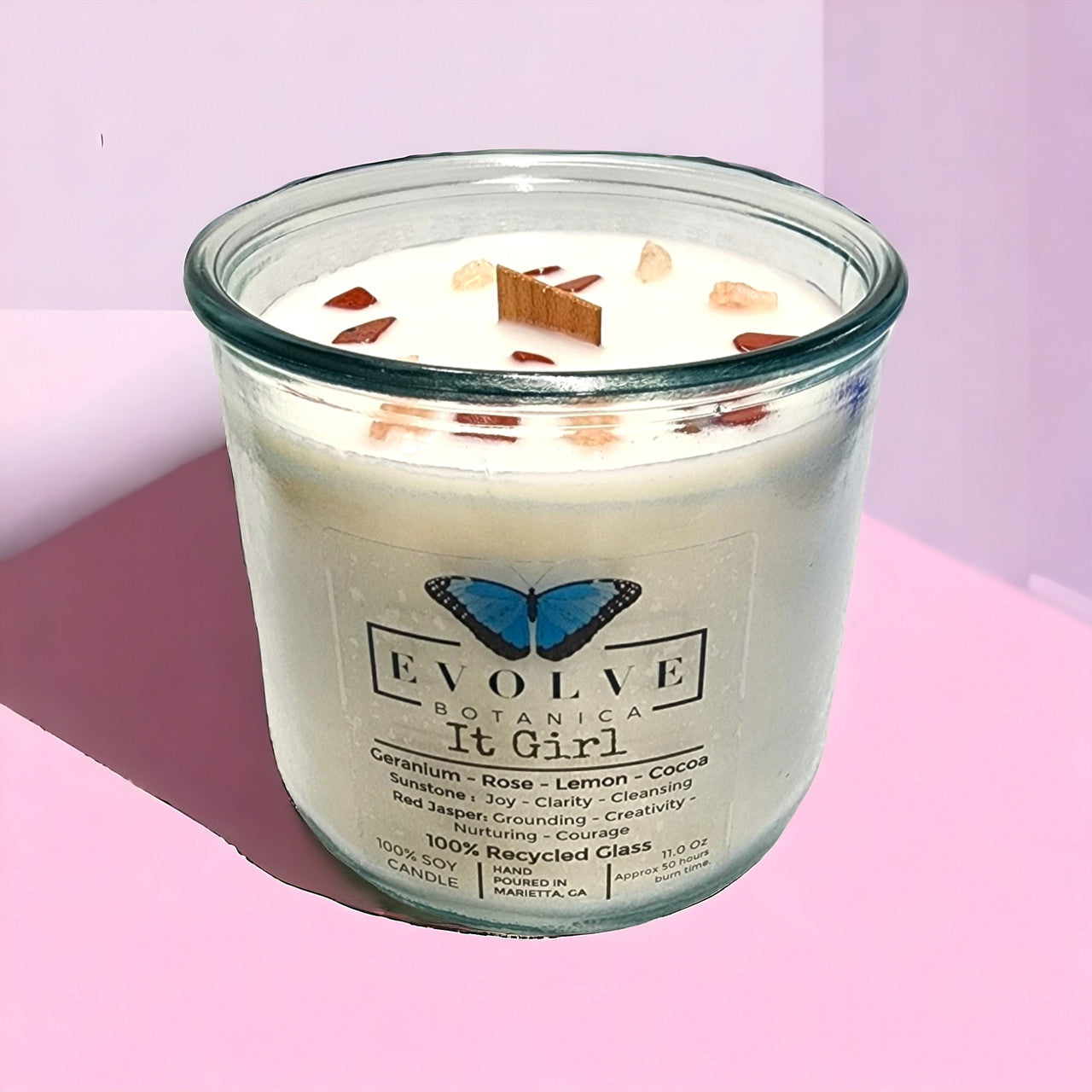 It Girl soy candle by Evolve Botanica with sunstone and red jasper gemstones, featuring a wood wick for a cozy glow.