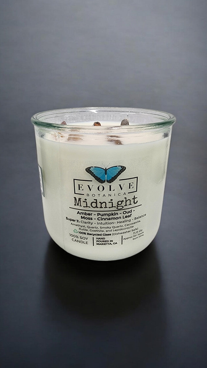 Evolve Botanica Midnight Rocks Candle with wood wick and Super Seven gemstone, soy wax, in a glass jar.