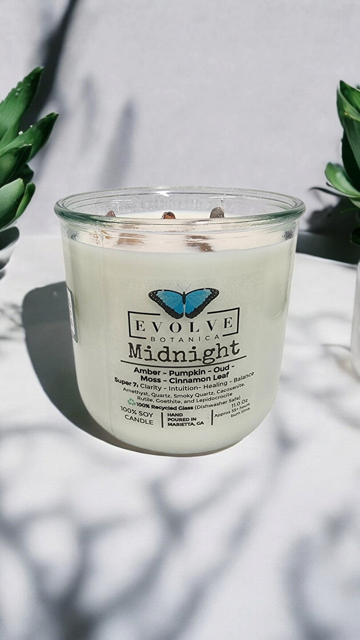 Evolve Botanica Midnight Rocks Candle with wood wick and Super Seven gemstone soy wax, featuring layered colors and textured surface.