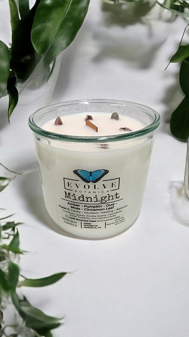 Evolve Botanica Midnight Rocks Candle with wood wick and Super Seven gemstone soy candle, featuring layered dark tones and gemstone accents.