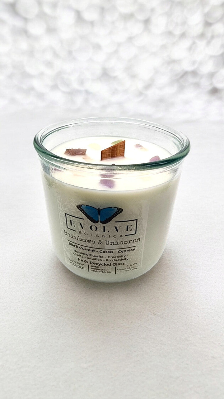 Evolve Botanica Rainbows & Unicorns soy candle with rainbow fluorite gemstone and wood wick, featuring colorful unicorn and rainbow design.